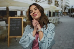 Mulher sorridente na rua, vestida casualmente, demonstrando felicidade e autoestima, com cenário urbano ao fundo, perfeito para ilustrar autoestima e bem-estar.