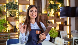 Garçonete sorridente com avental faz sinal de 